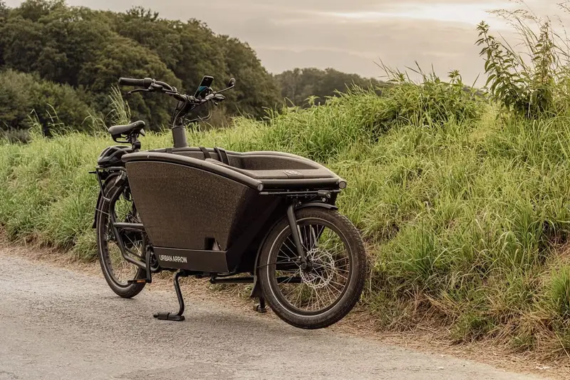 Zwarte bakfiets op een pad tussen het groen